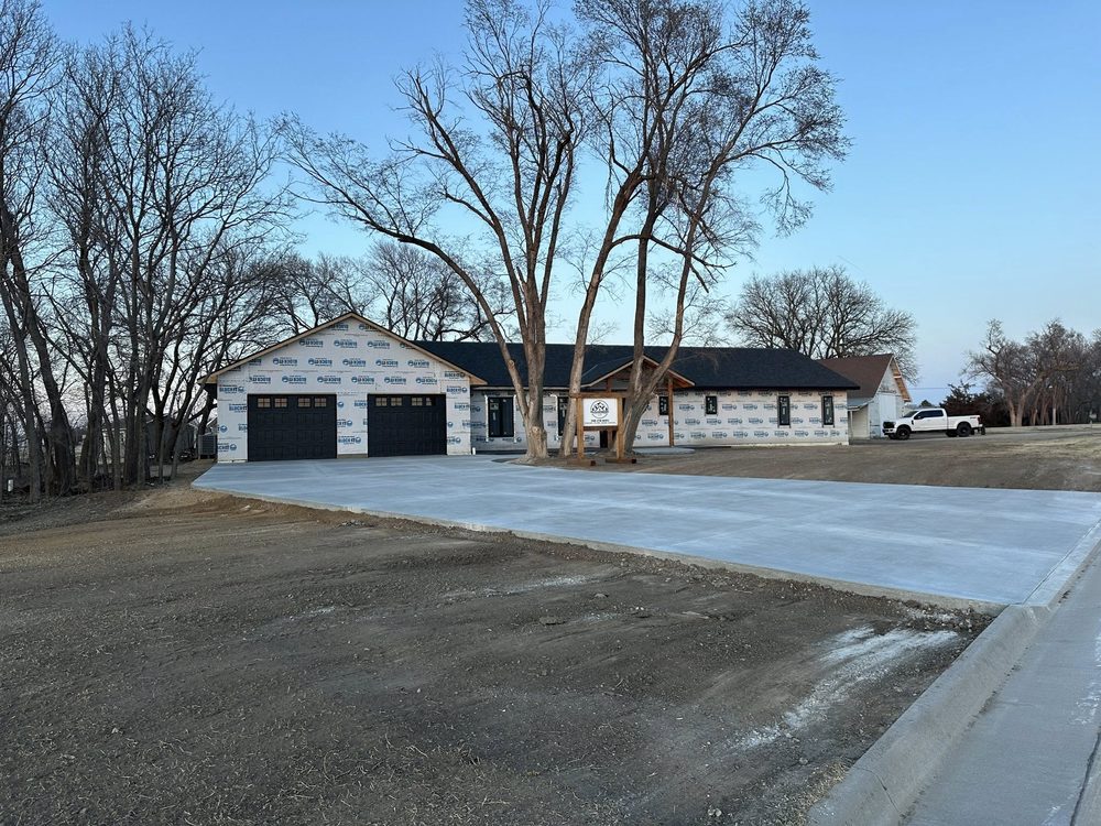 Custom home exterior with black garage doors and finished concrete drive