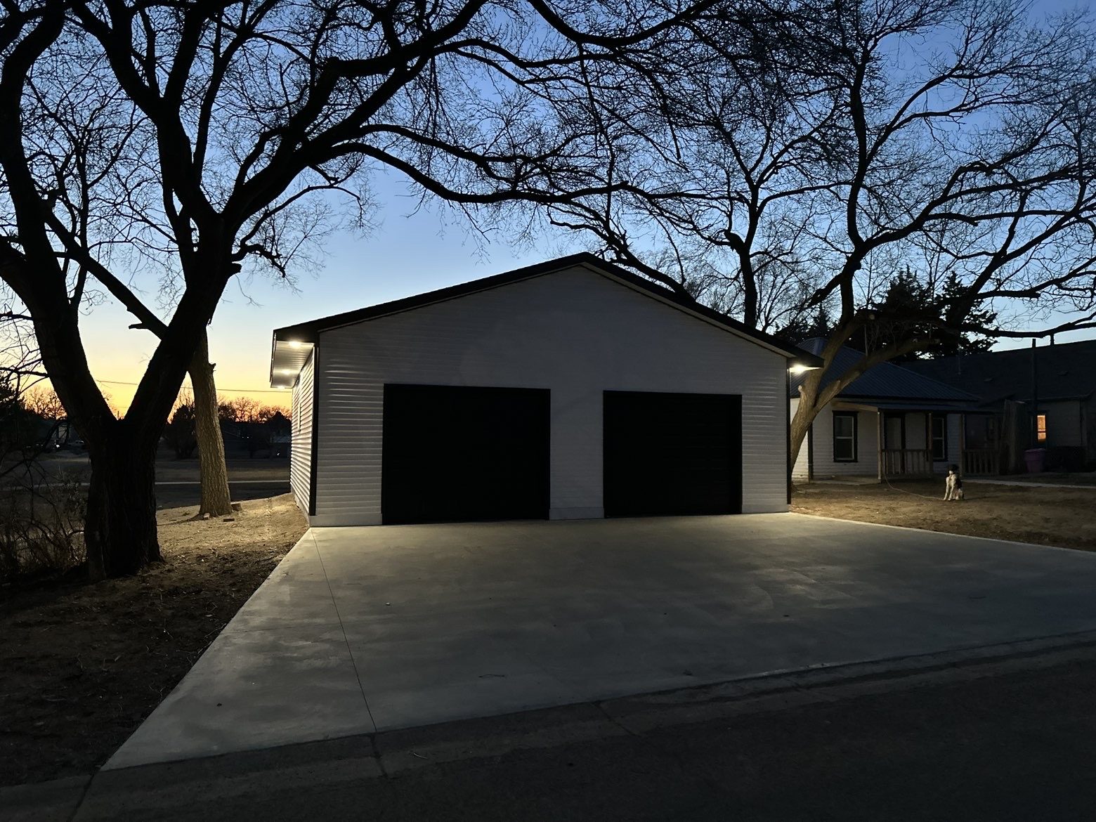 BlackRidge-built detached garage with black doors and finished concrete drive at twilight